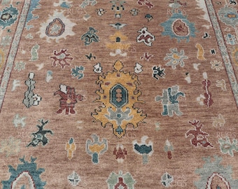 May include: A brown rug with a colorful geometric pattern. The rug has a central medallion with a teal and yellow design. The rug is made of wool and has a hand-knotted construction.