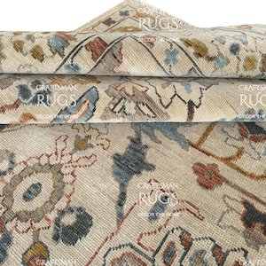 May include: Close-up of rolled beige rugs with intricate floral and geometric patterns in shades of blue, rust, and gold. The rugs have a distressed, vintage look, with visible text reading "Craftsman Rugs, Decor the Home."