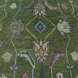 May include: A green rug with a floral pattern. The rug has a central diamond shape with a blue and white design. The rug is made of wool and has a soft texture.
