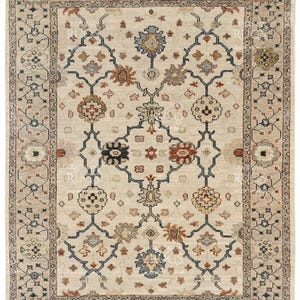 May include: A rectangular beige rug with an intricate floral pattern. The rug features a central design with repeating floral motifs in shades of brown, blue, and beige, framed by a detailed border.