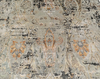 May include: A distressed-look rug with a muted color palette of gray, black, and touches of orange. The rug features an intricate, faded floral pattern, creating a vintage aesthetic. The design is detailed and textured, suitable for home decor.