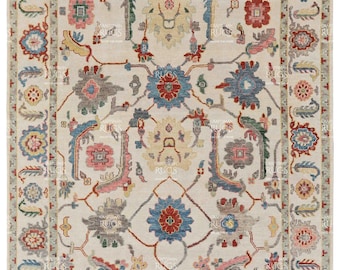 May include: A rectangular beige rug with an intricate floral pattern. The rug features a central medallion and a border with repeating floral motifs in shades of red, blue, yellow, and gray. The rug is a traditional style.