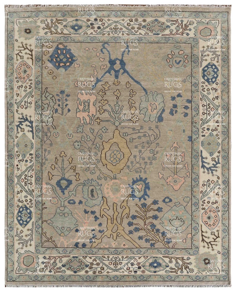 May include: A rectangular rug with a central beige field, adorned with detailed floral and geometric patterns in blue, pink, and beige. The rug features a patterned border with repeating motifs and the text "CRAFTSMAN RUGS DECOR THE HOME".