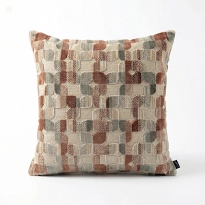 May include: Square decorative pillow with a textured geometric pattern in shades of beige, brown, and gray. The pillow has a soft, inviting appearance, suitable for adding a touch of style to any living space.