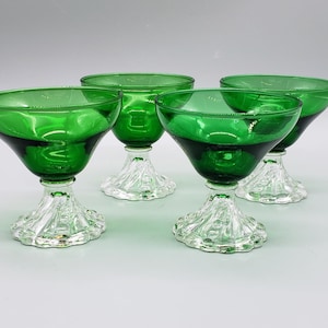 May include: Set of four green glass dessert dishes with clear glass stems. The dishes are round and have a scalloped edge.