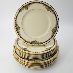 May include: A stack of 12 cream-colored dessert plates with a black and gold border. The plates have a delicate floral design in gold.