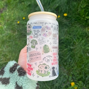 Puede incluir: Un vaso de vidrio esmerilado con tapa de bambú y pajita transparente. El vaso está cubierto de garabatos y texto, incluyendo frases como "I think I need you for keeps" y "This is a love story."