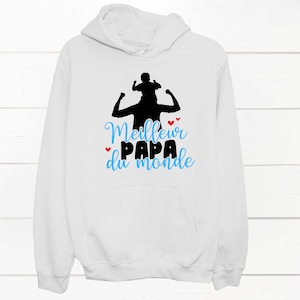 K&ouml;nnte beinhalten: Wei&szlig;er Hoodie mit einer schwarzen Silhouette eines Vaters, der ein Kind auf seinen Schultern tr&auml;gt. Der Text "Meilleur Papa du monde" ist in Blau und Rot auf dem Hoodie gedruckt.