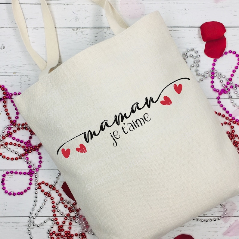 May include: A white canvas tote bag with black text that reads "maman je t'aime" and three red hearts.