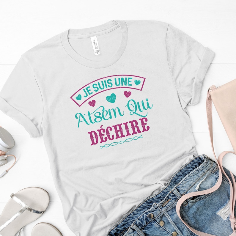 May include: White t-shirt with the text "Je suis une Atsem qui d&eacute;chire" in teal and pink with hearts around the text.