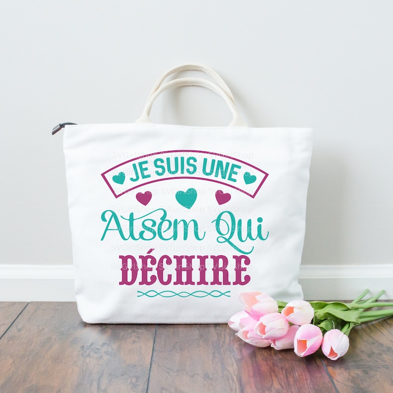 May include: White tote bag with a pink and teal design. The bag has the text "Je suis une Atsem qui d&eacute;chire" printed on it.