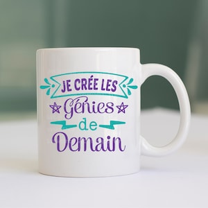 May include: White ceramic mug with a teal and purple design. The text on the mug reads "Je cr&eacute;e les g&eacute;nies de demain".
