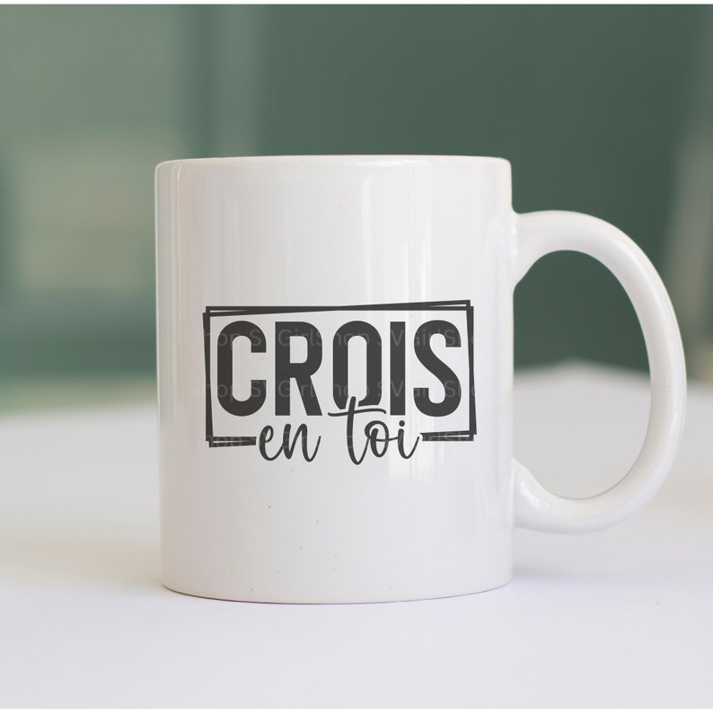 May include: White ceramic mug with a black graphic that says "CROIS en toi" in a rectangular frame.