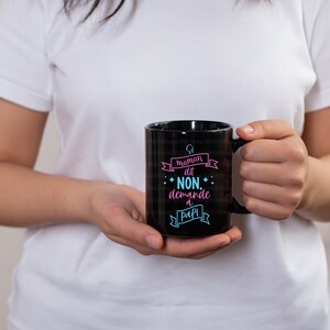 Peut inclure: Mug noir avec l'inscription "Si maman dit NON, demande &agrave; Papi" en rose et bleu. La tasse est tenue par une personne portant un t-shirt blanc. Le texte est dans un design de banni&egrave;re.