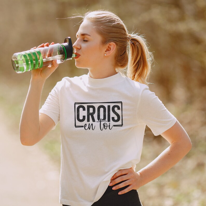 May include: White t-shirt with black text that reads "CROIS en toi" in a black rectangle.