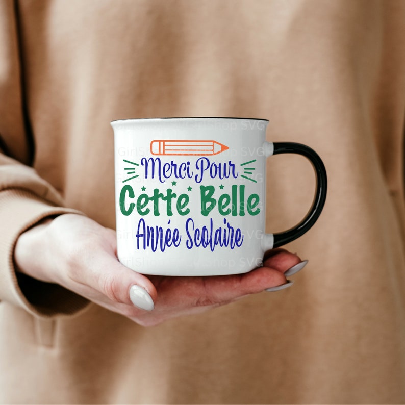 May include: White ceramic mug with a black handle. The mug has a black rim and a design of a pencil, stars, and the text "Merci Pour Cette Belle Ann&eacute;e Scolaire".