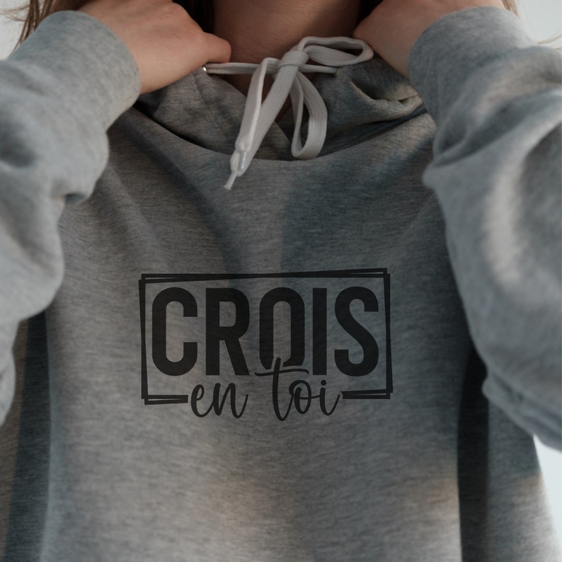 May include: Grey hooded sweatshirt with a black graphic that says "CROIS en toi" in a rectangular box.