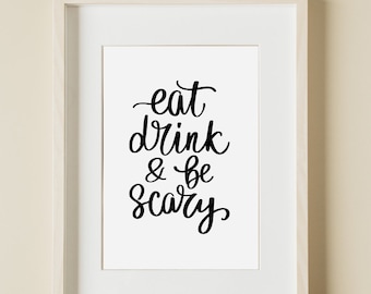 Puede incluir: Una impresión enmarcada en blanco con caligrafía negra que dice "eat drink & be scary". La impresión está en una pared beige con el texto "PRINT CODES DESIGN" debajo del marco.