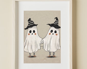 May include: A framed art print featuring two white ghosts holding hands, each wearing a black witch hat with white stripes, black and white striped leggings, and orange shoes, set against a tan background with the text PRINT CODES DESIGN.