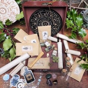 Peut inclure: Une collection d'objets mystiques disposés sur une surface en bois. Comprend des bocaux, des rouleaux, de petites bouteilles, une boîte en bois et un calendrier circulaire. Le houx vert et les baies rouges ajoutent une touche naturelle.
