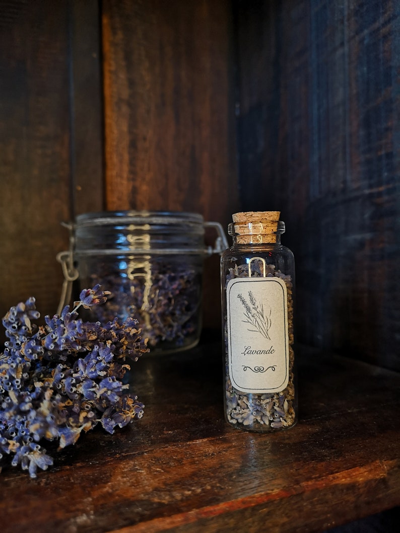 May include: A small glass jar with a cork lid filled with dried lavender flowers. The jar has a label that says "Lavande" in cursive writing.