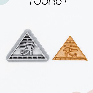 Può includere: Due tagliabiscotti stampati in 3D a forma di piramide con il simbolo dell'occhio di Horus. Il tagliabiscotti a sinistra è argentato e quello a destra è dorato.