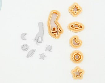 May include: A set of 3D printed cookie cutters in a light beige color. The cutters are shaped like a hand, a star, a crescent moon, a sun, a planet, and a circle. The cutters are arranged on a white surface. 3D PRINTED cutter PLA plant-based plastic, non-toxic