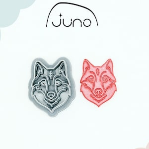 Puede incluir: Dos cortadores de galletas con forma de lobo. Uno es gris, el otro es rojo. Los cortadores están impresos en 3D y hechos de plástico vegetal no tóxico. La palabra "juno" está encima de los cortadores.