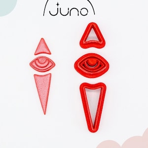 May include: Two red 3D printed cookie cutters shaped like stylized eyes with a triangle shape at the top. The cutters are made of PLA plant-based plastic and are non-toxic. The brand name "Juno" is printed in black at the top of the image.