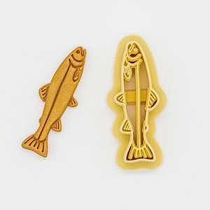 May include: A 3D printed cookie cutter in the shape of a fish. The cutter is made of PLA plant-based plastic and is non-toxic. The cutter is shown next to a smaller version of the fish, which is the actual cookie cutter.