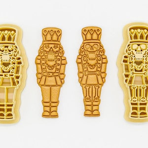 May include: Three gold-coloured 3D printed cookie cutters shaped like nutcrackers. The cutters are made of PLA plant-based plastic and are non-toxic. 3D PRINTED cutter PLA plant-based plastic, non-toxic