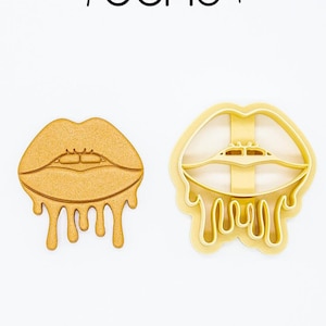 Op de afbeelding: Twee koekjesvormen in de vorm van druipende lippen. De vorm links is massief goud, terwijl de vorm rechts een holle omtrek heeft.