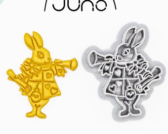 May include: Two bunny-shaped cookie cutters. One is gold, the other is silver. The bunnies are dressed in a jacket and holding a horn. The text "juno" is above the cutters. Below the cutters is the text "3D PRINTED cutter" and "PLA plant-based plastic, non-toxic".