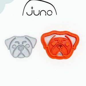 May include: Two 3D printed cookie cutters in the shape of a pug dog face. The cutter on the left is silver and the cutter on the right is orange.