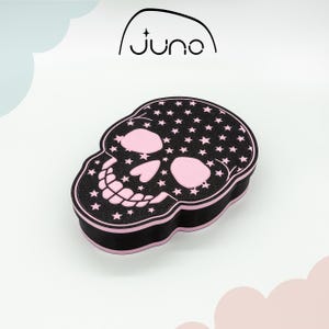 May include: Black skull-shaped box with pink stars and pink details. The box is made of foam and has a smooth surface.