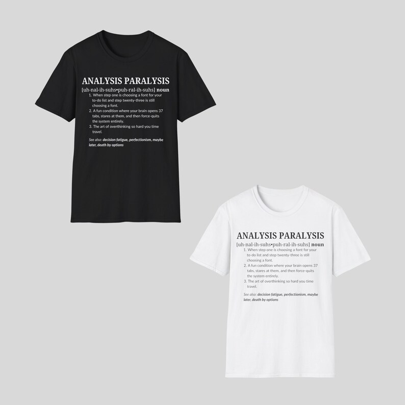 May include: Two t-shirts, one black and one white, each with the text "ANALYSIS PARALYSIS" and a definition. The definition includes the phrase "choosing a font" and other humorous descriptions of overthinking.