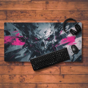 May include: A black and grey gaming mouse mat with a skull design and pink accents. A black keyboard and a black headset are on the mouse mat.