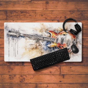 May include: A watercolor painting of an electric guitar with a red, orange, and yellow body. The guitar is on a white background with splashes of watercolor paint. A black keyboard and a black wireless mouse are also in the image.