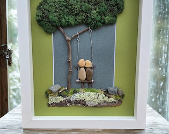 Framed Pebble Art - Couple on a Swing with green/gray background