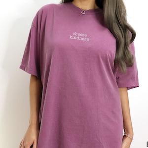 K&ouml;nnte beinhalten: Ein lilafarbenes Oversize-T-Shirt mit dem Aufdruck "choose kindness" auf der Vorderseite.