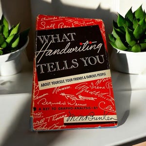 May include: A red and black book titled "What Handwriting Tells You" with the subtitle "About Yourself, Your Friends & Famous People". The book cover features a key to grapho-analysis by M.N. Bunker.