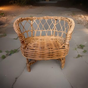 Könnte beinhalten: Ein kleiner, gewebter Korbstuhl mit abgerundeter Rückenlehne und Armlehnen. Der Stuhl ist aus hellbraunem Korbgeflecht gefertigt und hat eine gewebte Sitzfläche. Der Stuhl ist für ein Kind oder ein kleines Haustier konzipiert.