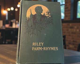 May include: A vintage hardcover book titled "Riley Farm-Rhymes." The cover is dark green with gold lettering and an illustration of a man in a field. The book is standing upright on a wooden surface.