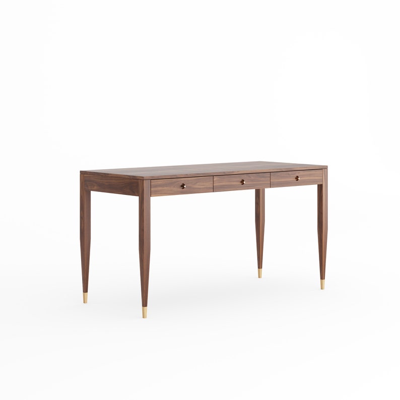 May include: A dark brown wooden desk with three drawers and brass hardware. The desk has a rectangular top and tapered legs.