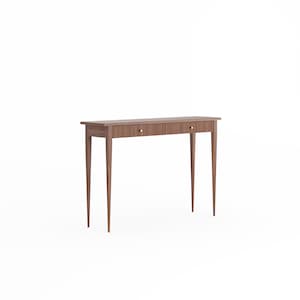 Könnte beinhalten: Ein brauner Holz-Konsolentisch mit zwei Schubladen und spitz zulaufenden Beinen. Der Tisch hat ein schlichtes, elegantes Design.