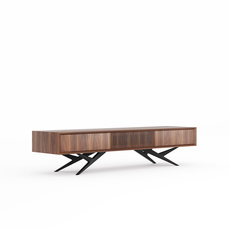 May include: A walnut wood media console with a low profile. The cabinet has two solid doors and a central section with vertical slats. It stands on black, angled metal legs, offering a mid-century modern design. The console is approximately 180 cm long.