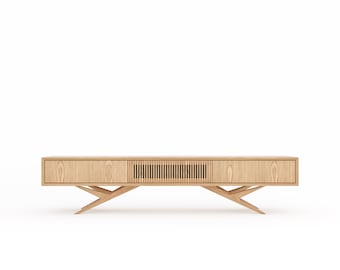 May include: A long, low wooden entertainment center with two doors and a slatted panel in the center. The cabinet has a light wood finish and sits on a set of angled legs.