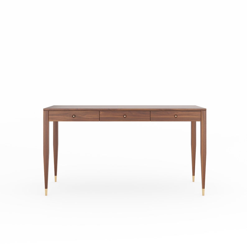 May include: A dark brown wooden desk with three drawers and brass hardware. The desk has tapered legs and a rectangular top.