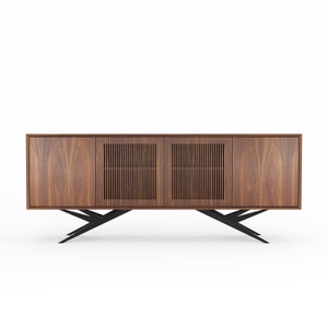 May include: A long, rectangular wooden cabinet with three doors. The cabinet has a dark wood finish and black metal legs. The centre door has a slatted design.