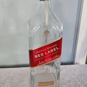 May include: Empty glass bottle with a red label that says "JOHNNIE WALKER - RED LABEL BLENDED SCOTCH WHISKY John Walker & Sons ESTABLISHED 1820"